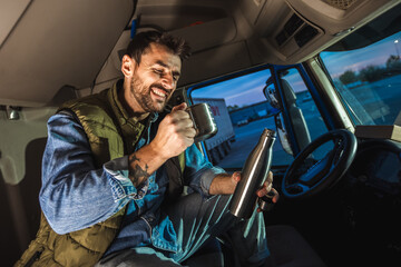 Young handsome man driving long vehicle and drinking coffee so he could get some energy.