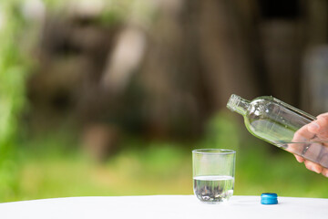 close up of male hand pouring water from bottle into glass, pouring glass of water, bottle of glass water filling copy space