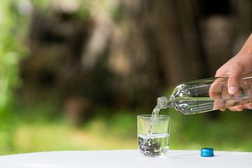 close up of male hand pouring water from bottle into glass, pouring glass of water, bottle of glass...