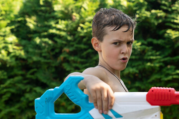 Funny boy with an amazing smile holding a water gun on the backyard	