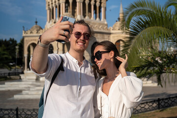 Young couple tourists make selfie in the ancient European city center. Explorers have trip to...
