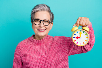 Photo of optimistic nice woman with short hair dressed pink sweater in glasses hold alarm manage time isolated on teal color background