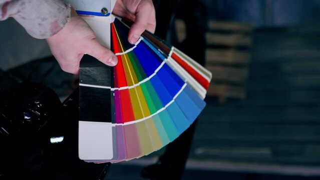 vertical video close-up of hand at a service station a master master selects paint color on a color palette