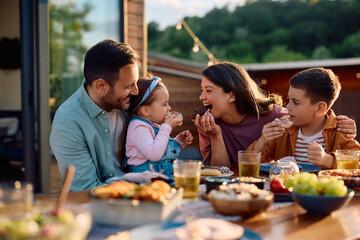 Happy family having fun while eating donuts at picnic table on  patio.