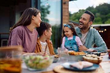 Happy family talking while enjoying in lunch on patio.