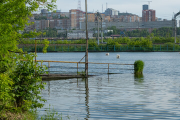 The overhead pier sank into the water. The pier went underwater against the background of the city in sunny weather