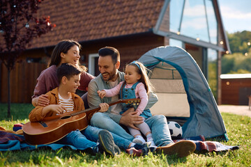 Little boy playing acoustic guitar during family camping.