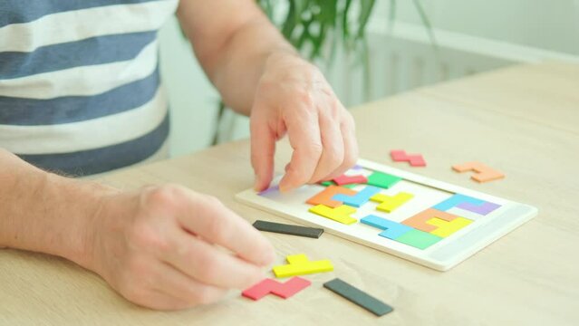 senior man's engaged hands skillfully maneuver colorful wooden pieces brain teaser puzzle, highlighting importance mental stimulation and cognitive health in combating dementia and Alzheimer's disease