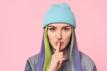 Young caucasian teenage woman girl hipster showing silent gesture finger on lips for secret rumor...