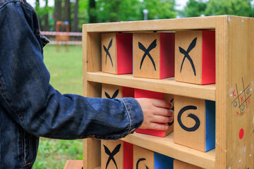 Close-Up hand of child playing wooden Tic-Tac-Toe outdoors. Playful and educational fun and outdoor...
