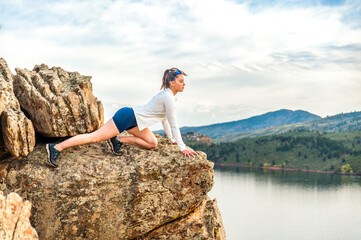 Young woman climbing on rocks above lake