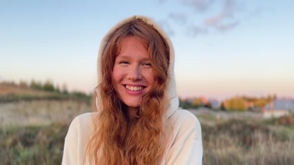 young cute woman dreaming and praying outdoors at sunset or sunrise in the park