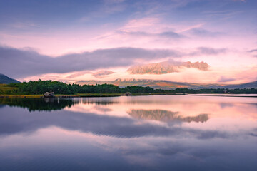 Spectacular reflection of the mountains on a lake with mist under the midnight sun, fairy tale...