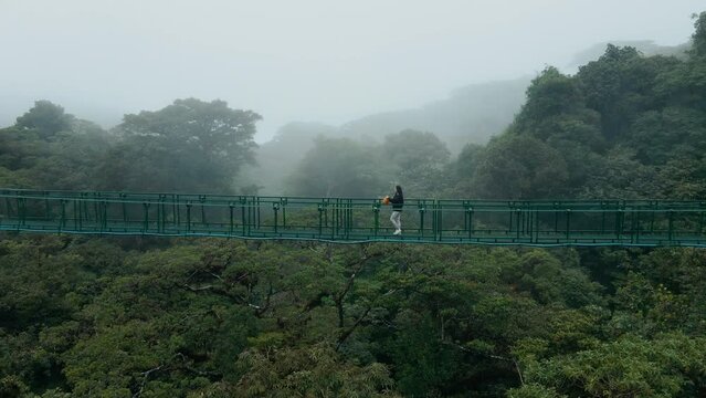 Solitary traveler on misty suspension bridge in Costa Rica