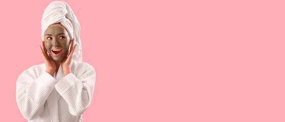 Happy young woman with applied clay mask on pink background