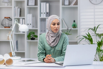 Woman in hijab designer working in home office, architect using laptop at work, studying technical...
