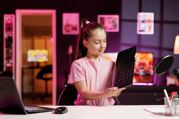 Small girl showing subscribers mechanical keyboard received from sponsoring brand to promote it....