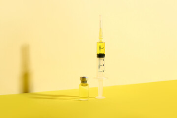 Medical syringe with medicine and ampoule on yellow background