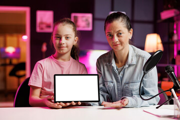 Cute girl and her mom filming unboxing mockup tablet popular among children watching her online...