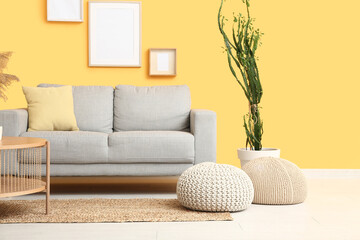 Interior of modern living room with houseplant, sofa and poufs