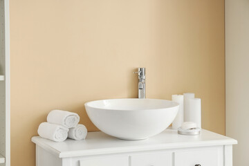 Ceramic sink, clean towels and candles in bathroom