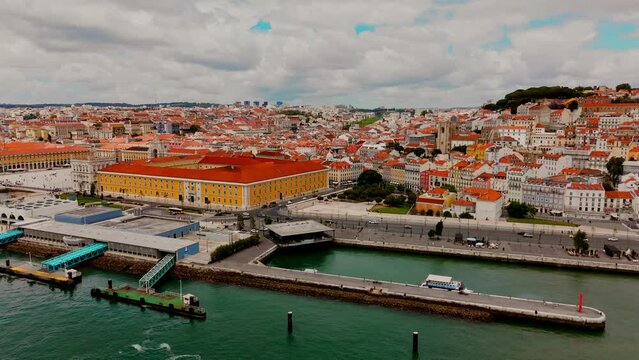 Aerial view of Lisbon downtown on a sunny day with epic cloudy sky. Flying up from Tagus River to Paco do Arco. 