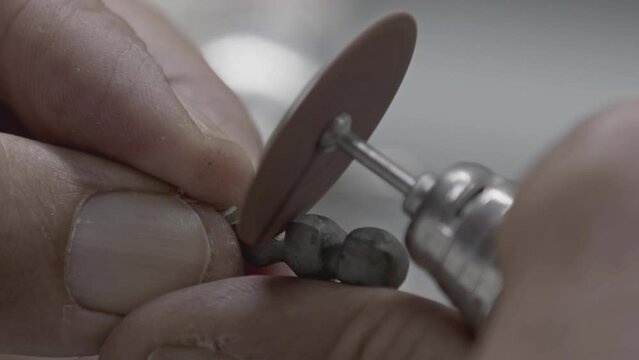 Dental Technician Rounds the Metal Substructure of Implant Prosthesis Teeth by Cutting It with a Milling Machine Footage.