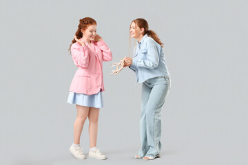 Stylish redhead sisters with new high heels on grey background