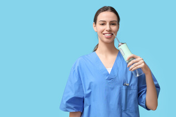 Female dentist with oral irrigator on blue background