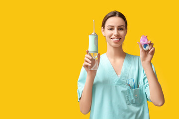 Female dentist with oral irrigator and dental floss on yellow background