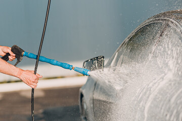 Worker washing car at self-service car wash