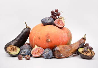a large pile of various spoiled vegetables and fruits. moldy pumpkin, grapes, avocados, eggplants,...