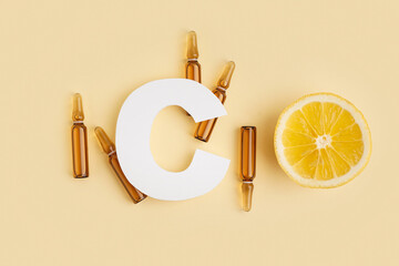 Paper letter C, ampules and lemon on color background