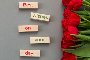 Card with the inscription Best wishes on your day! Bouquet of red tulips on a gray background