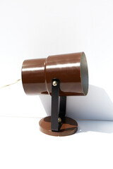 A photograph of a vintage metal, brown, can, desk lamp.
