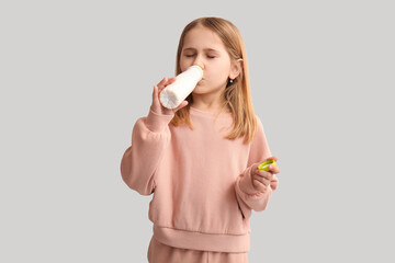 Cute little girl drinking yogurt on white background