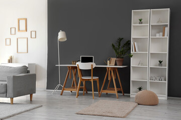 Modern workspace with white desk, standard lamp and bookshelf in living room