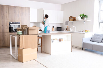 Male janitor opening cupboard in kitchen on moving day, back view