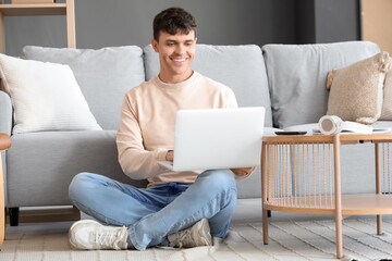 Young man using laptop on floor at home