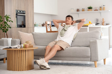 Young man resting on sofa in kitchen