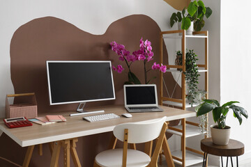 Fototapeta premium Workplace with computer, laptop and orchid flower in stylish office