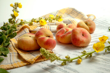 Several whole saturn peaches or flat peach on white wooden background..