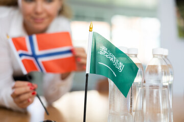 Little flag of Saudi Arabia on table with bottles of water and flag of Norway put next to it by...