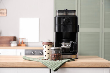 Modern coffee machine, beans and paper cup on wooden table in kitchen