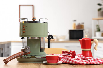 Modern coffee machine, cup of espresso and cake on wooden table in kitchen