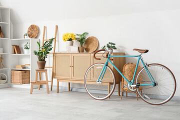 Interior of living room with bicycle and yellow narcissus flowers on wooden cabinet