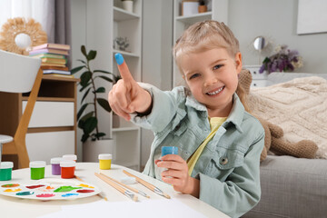 Cute little girl with paints at home