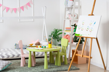 Interior of children's bedroom with easel and paints on table