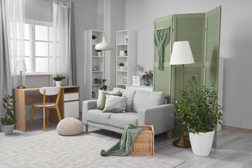 Interior of living room with green folding screen, sofa and plants