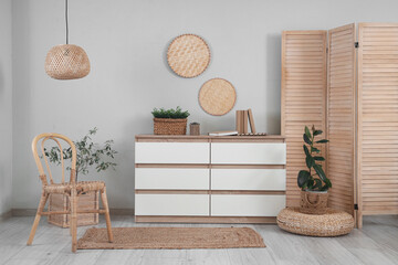 Interior of living room with wooden folding screen, chair and commode